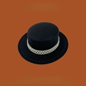 Detalle de elegante sombrero de fieltro negro con cadena de perlas de tres capas decorativa