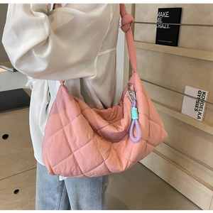 Detail of pink quilted tote bag with colorful braided cord worn by a model