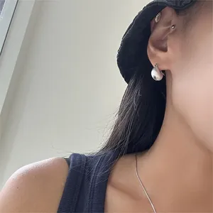Close-up of minimalist silver hoop earrings worn by a model with a polished shiny finish