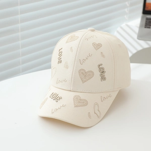 Gros plan d'une casquette beige pour enfant avec broderie LOVE dorée et cœurs