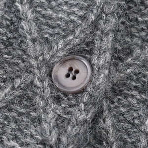 Dettaglio ravvicinato di un cardigan grigio a trecce con bottone marrone