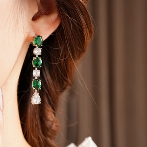 Boucles d'oreilles pendantes avec pierres émeraude et zircon sur un mannequin