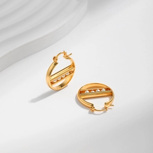 Detail der 18K vergoldeten runden Ohrringe mit weißen Perlen im strukturierten Design