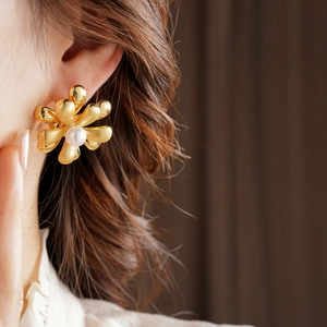 Detailed view of vintage gold flower earring with a central pearl on a model's ear