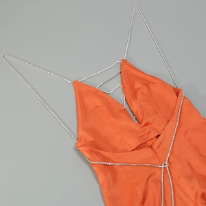 Detail of orange satin romper with deep V-neck and sparkling rhinestone chain straps