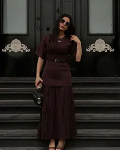 Detail of dark red two-piece dress set with pleated skirt and waist belt accessory