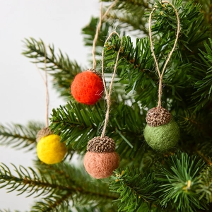 Set of four colorful wool felt acorn ornaments with natural caps hanging on Christmas tree