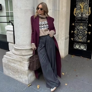 Élégant trench-coat bordeaux à revers porté avec un pull à col roulé et un pantalon large