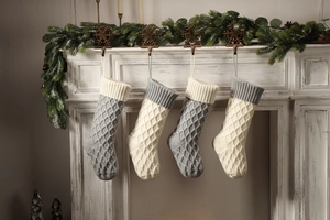 Nahaufnahme von vier gestrickten Weihnachtsstrümpfen mit Rautenmuster am Kamin simsi