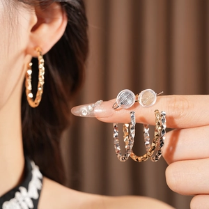 Detail of twisted geometric C-shape clip-on earrings in gold and silver finish with silicone pads