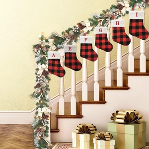 Plaid Christmas stockings with red letter embroidery hanging on a festive staircase