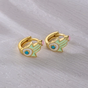 Golden Hamsa Hand earrings with green enamel and blue gemstone on a white texture