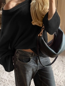 Elegant off-shoulder black knit sweater paired with a crescent gold chain shoulder bag