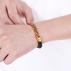 Men's gold Cuban chain bracelet with black lava beads and skull charm on wrist