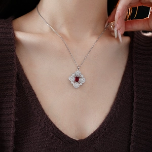 Detail of silver clover necklace featuring a red rectangular gemstone and zircons