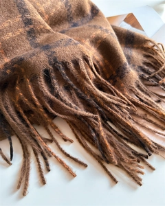 Close-up of brown plaid cashmere-like scarf showing soft knit texture and tassel edges