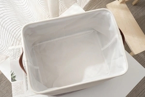 Detail view of cotton linen storage basket with faux leather handles and white lining