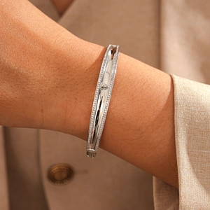 Detail of silver crown bangle featuring crystal borders and polished finish on a model