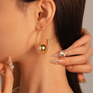 Modern geometric spiral hoop earrings with gold plated beads shown on model