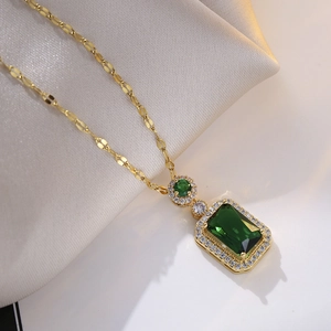 Close-up of emerald pendant necklace with zircons on elegant silk fabric background