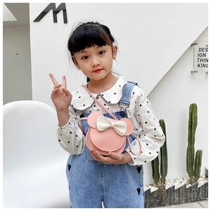 Pink girl's crossbody bag with cartoon mouse ears and white bow detail held by a model