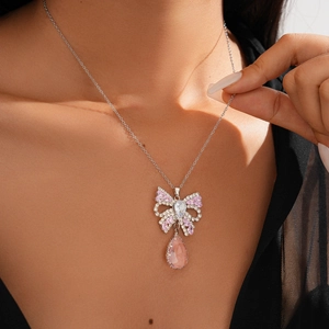 Close-up of elegant bow pendant with pink teardrop crystal on silver chain necklace