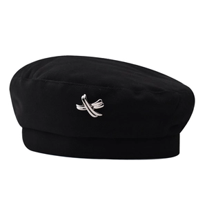 Detail of black wool beret with stylish silver X-shaped metal buckle on a white background