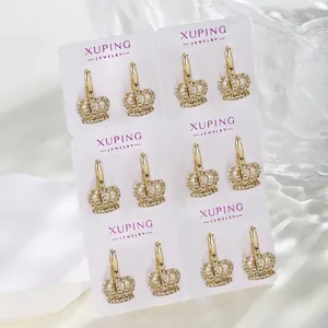 Macro detail of six pairs of gold crown earrings with pave white zircons on a display card