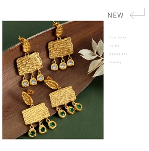 Detail of vintage gold earrings with textured metal and sparkling zircon tassels