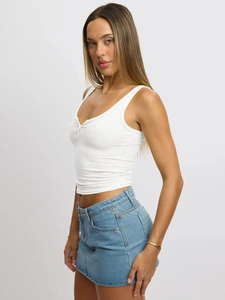 Side view of white ribbed knit tank top with U-neck and buttons paired with denim skirt