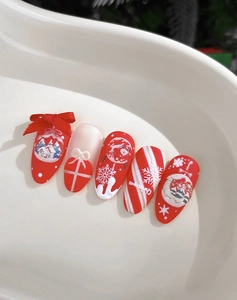 Detail of red and cream Christmas nails with 3D embossed snowflakes and bow charms