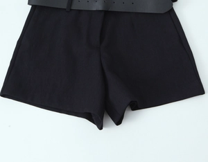 Flat lay of black woven shorts with matching belt and buckle on a plain white background
