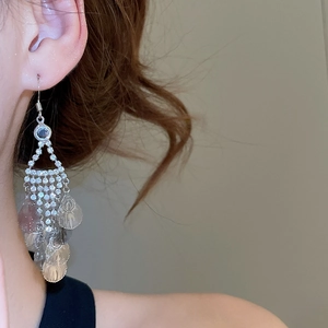 Macro view of long leaf tassel earrings with sparkling rhinestones worn on a model