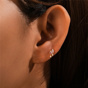 Macro view of gold s925 silver ear stud with pink and purple marquise stones on model's ear