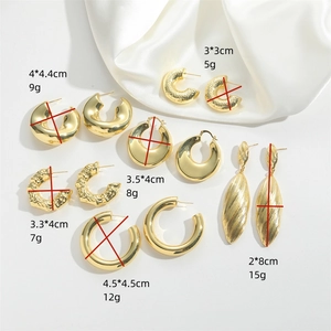 Brushed gold hoop earring set with C-shape rings and teardrop pendants on white silk