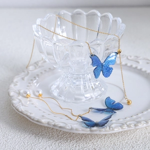 Schmuckset aus goldener Schmetterlingskette und Perlenohrringen mit blauen Glitzerdetails