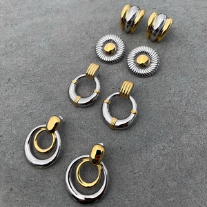 Four pairs of two-tone gold and silver stainless steel earrings on a gray background