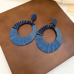 Oval denim patchwork earrings with silver needles and blue fabric textured design