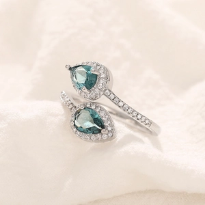 Macro view of teardrop emerald-green gemstones on a silver adjustable ring band