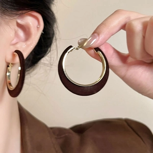 Close-up of vintage round hoop earrings with dark brown wood texture and gold metal accents