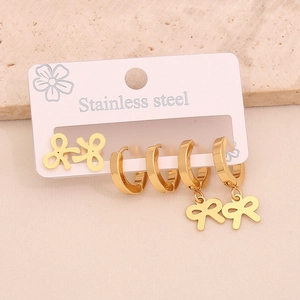 Close-up of three pairs of gold stainless steel earrings with bow and hoop designs