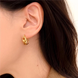 Close-up of golden twisted rope earrings worn by model for elegant minimalist style