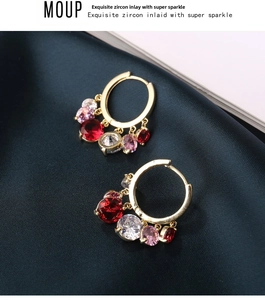 Detail of gold hoop earrings with cascading colorful zircons on blue silk background