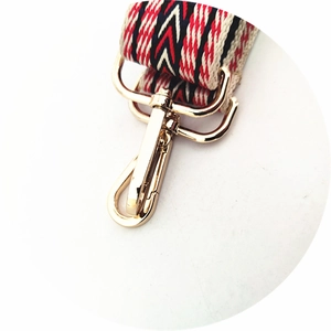 Detail of golden metal lobster clasp and red geometric ethnic style woven strap texture