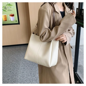Minimalist beige leather tote bag featuring brown straps and elegant vertical stitching