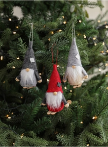Three handmade ski gnomes hanging on a Christmas tree with warm fairy lights