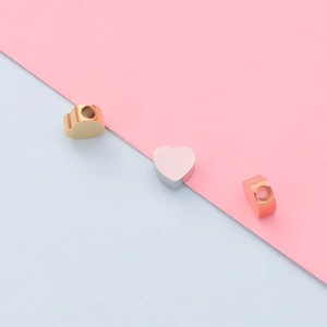 Macro detail of heart-shaped stainless steel beads in gold, silver and rose gold finishes