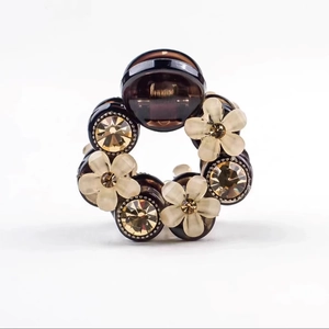 Detail view of amber resin hair claw with camellia flowers and sparkling crystals