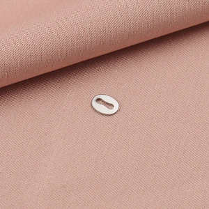 Macro detail of a silver stainless steel oval connector tag on pink textured fabric
