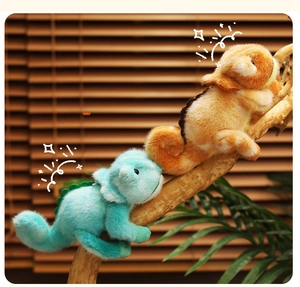 Gros plan de peluches caméléons bleues et orange grimpant sur une branche de bois